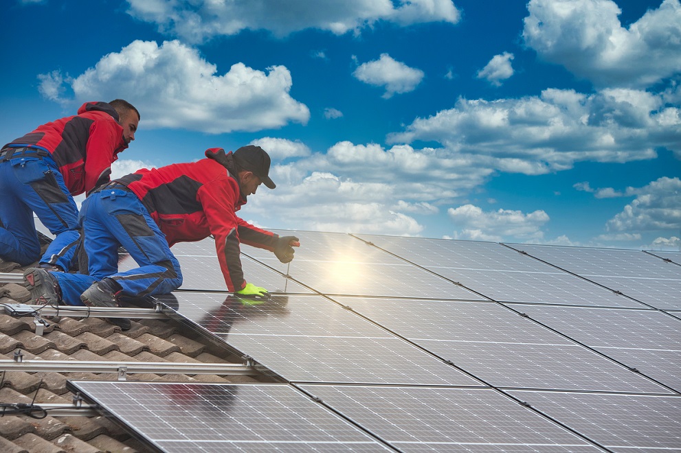 Zwei Techniker bringen eine Photovoltaikanlage auf einem Dach an