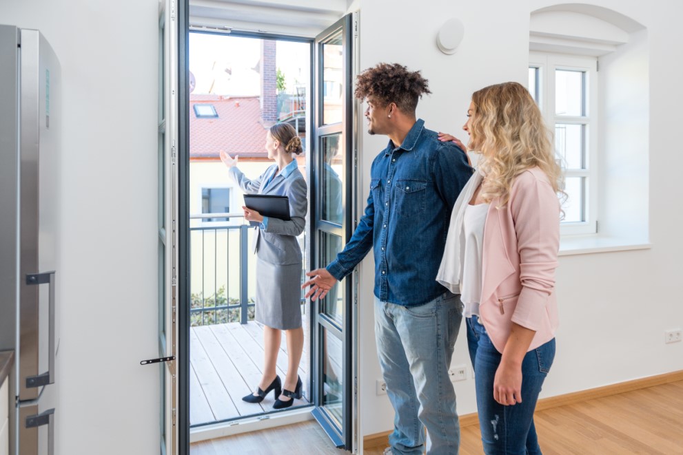 Maklerin zeigt Paar Aussicht vom Balkon