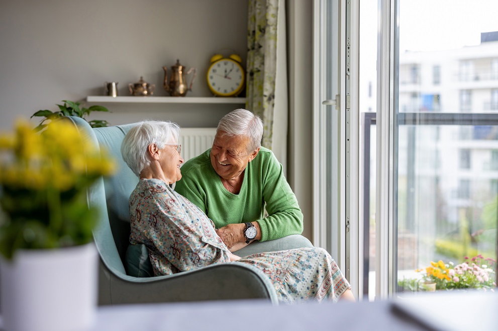 Zwei Senioren sitzen in einer traditionell eingerichteten Wohnung